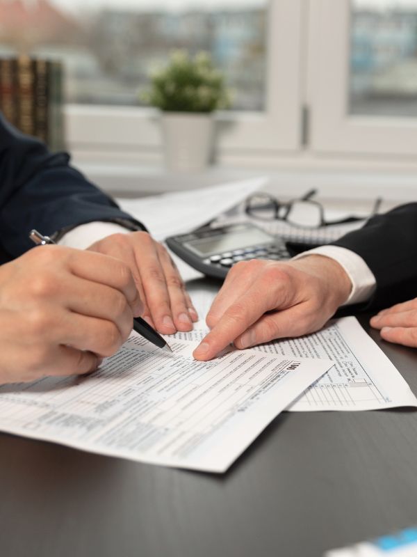 Two people are signing a form on top of papers.